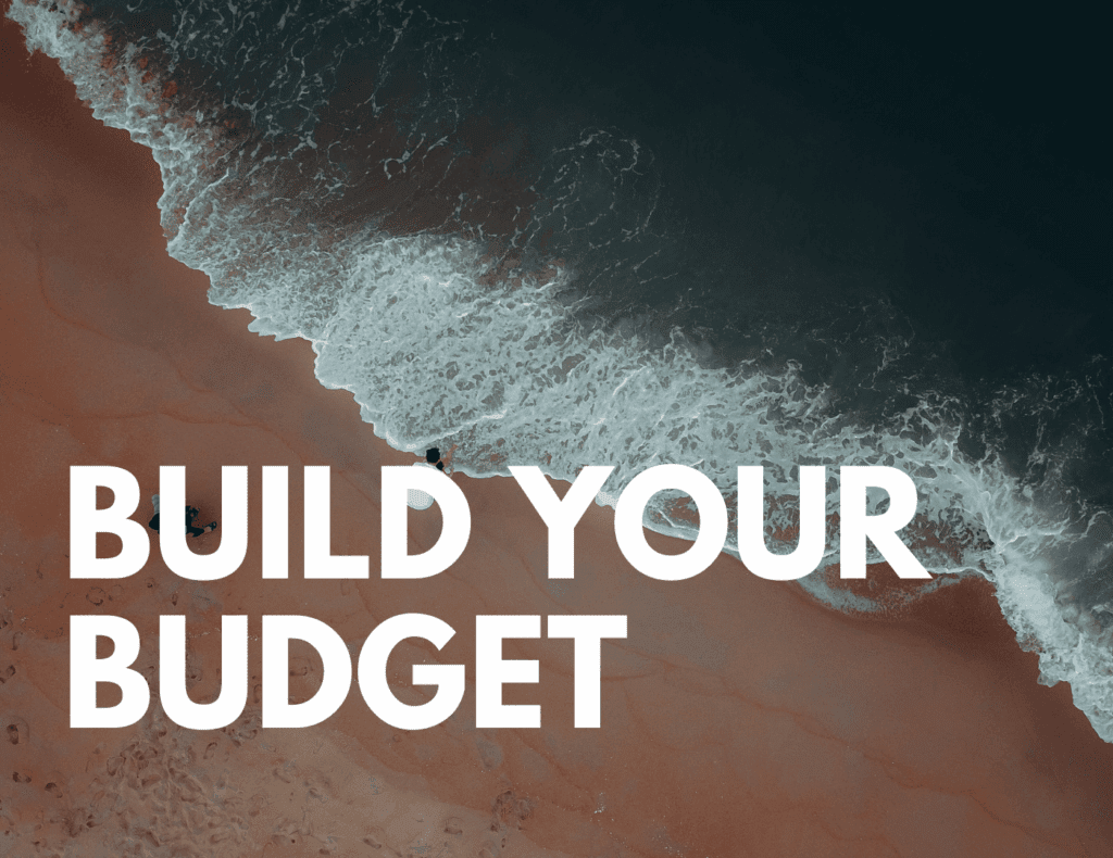 Aerial beach view with waves on red sand — represents building a realistic family travel budget.