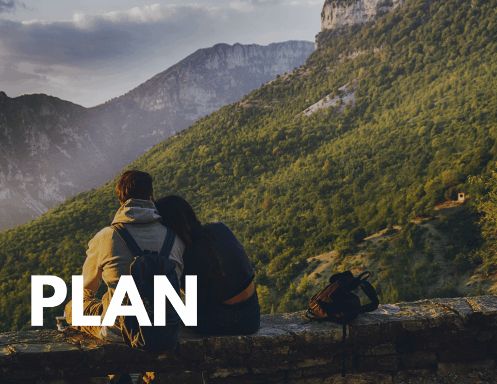 Couple sitting on a mountain ledge overlooking a valley — symbolizes long-term family travel planning.