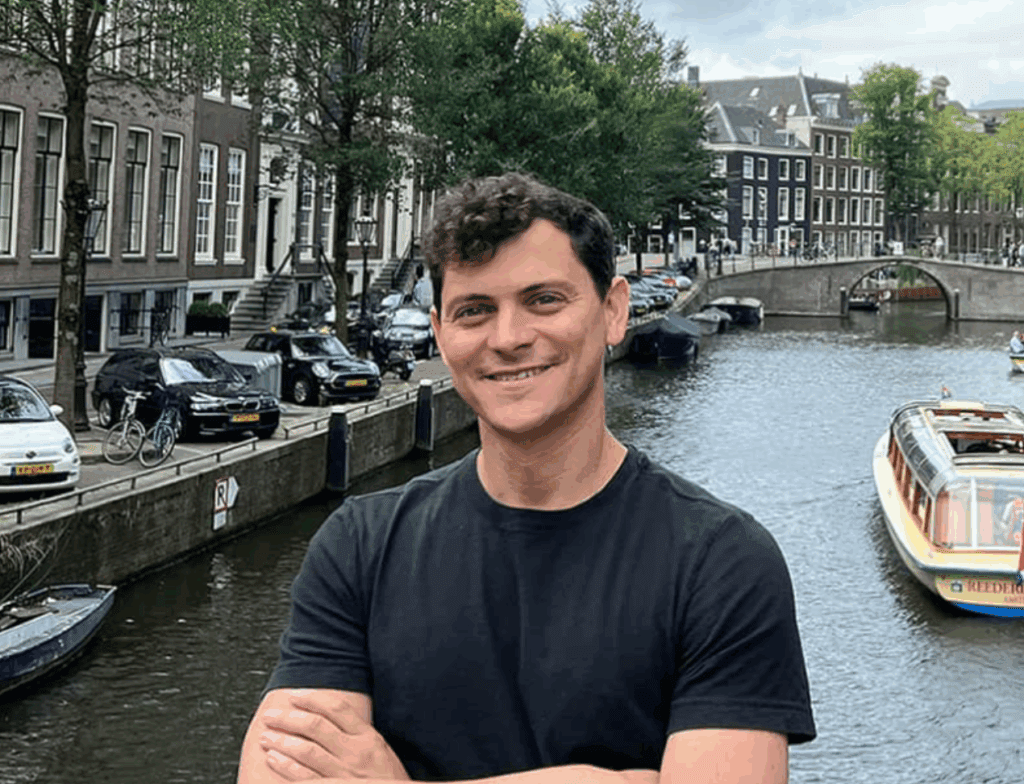 Nomadic Matt standing in Amsterdam by a canal, smiling — founder of one of the best travel blogs for budget and solo travelers in 2025.