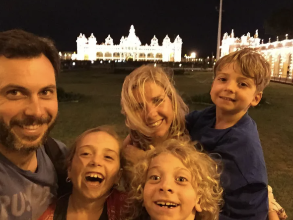The 5 Lost Together family smiling in front of a lit-up palace at night — a top travel blog for family adventures, global education, and nomadic life.