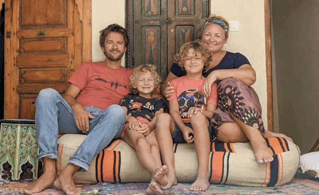 he Travellyne family sitting together on a Moroccan cushion outside a wooden door — one of the best family travel blogs for storytelling, culture, and slow travel in 2025.