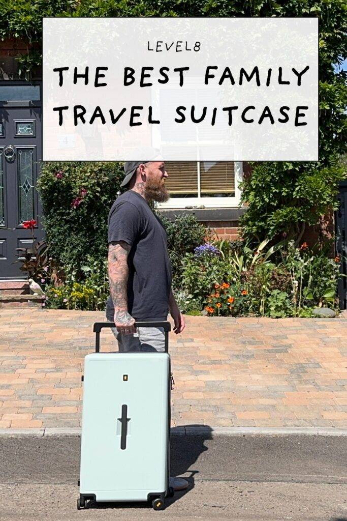 Bearded dad pulling mint Level8 suitcase down a brick driveway in bright sunshine