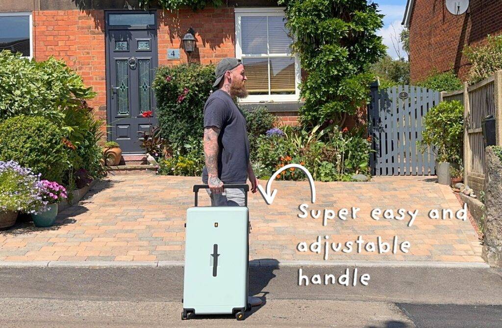 Man demonstrating adjustable handle of mint green suitcase