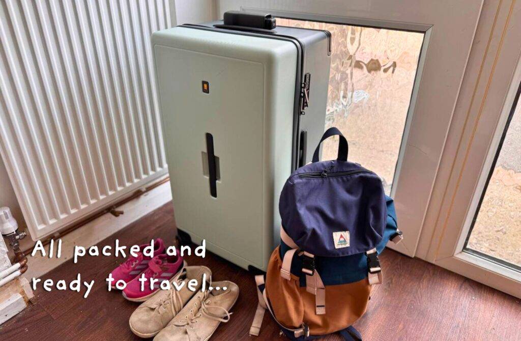 Packed suitcase with shoes and backpack by front door