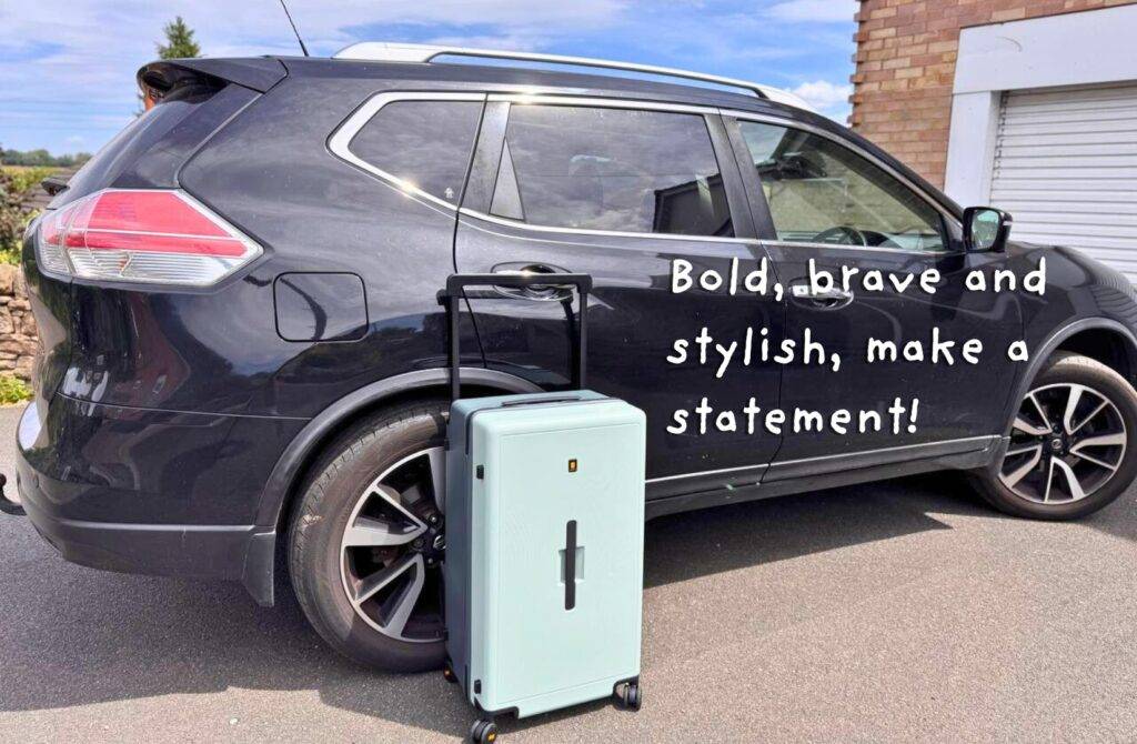 Mint green suitcase next to parked car on driveway