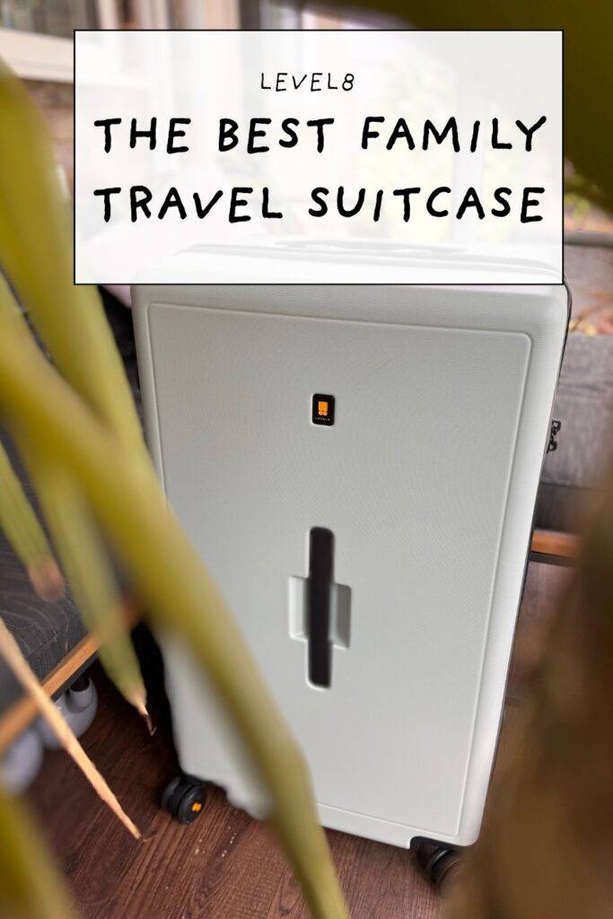 Angled view of Level8 suitcase partially obscured by indoor plants