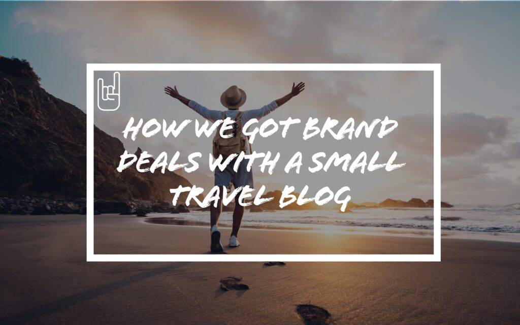 Man with backpack standing on beach at sunrise with arms raised – text overlay says "How We Got Brand Deals With A Small Travel Blog"